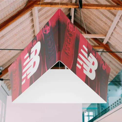 Suspended square-shaped trade show hanging sign with red and white branding, displayed in an indoor space with visible ceiling beams.